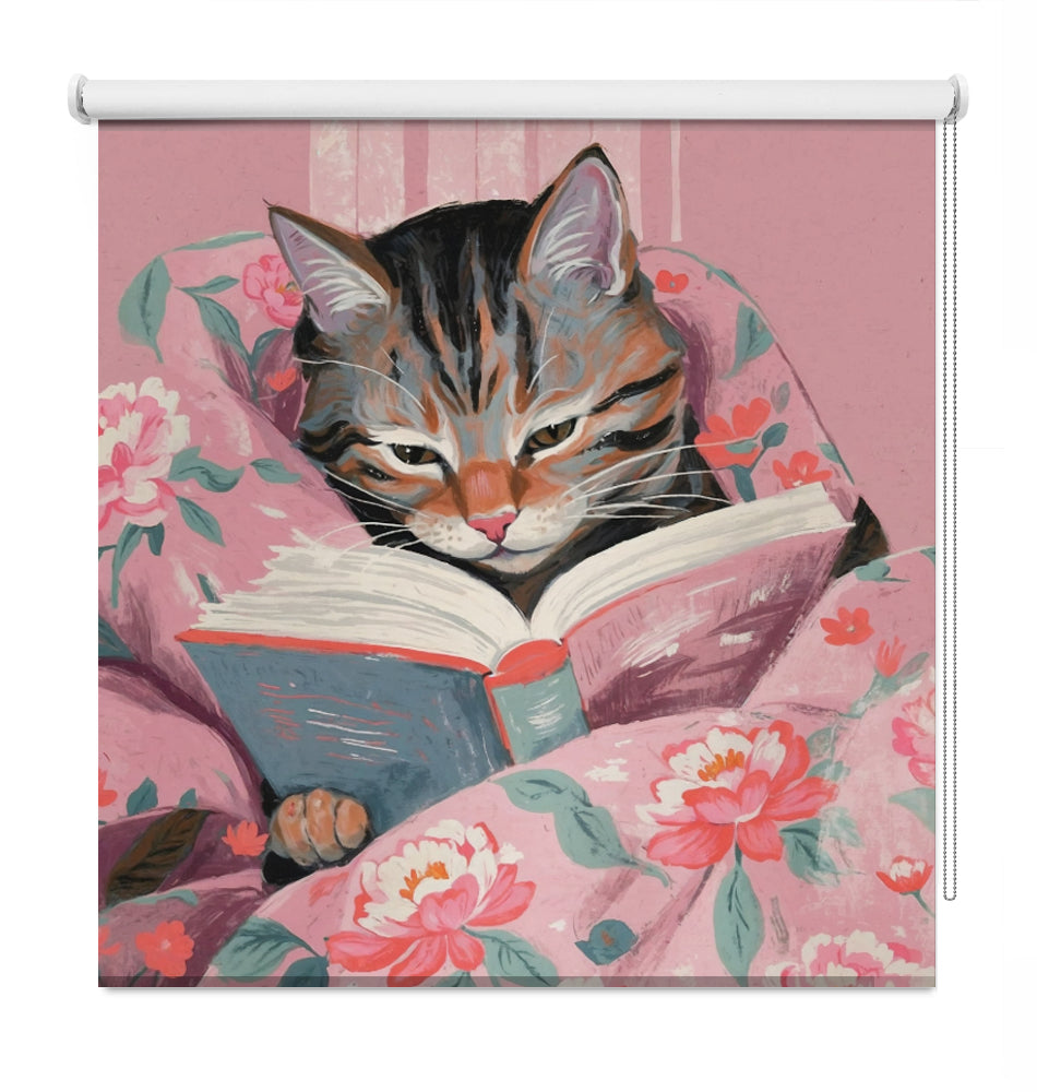 Printed roller blind featuring a whimsical illustration of a tabby cat reading a book wrapped in pink floral bedding