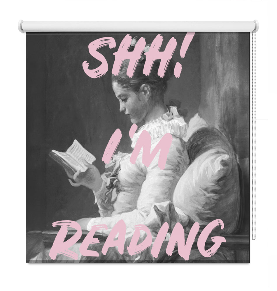 Printed roller blind featuring a black and white vintage painting of a woman reading a book, overlaid with the bold pink text SHH! I'M READING