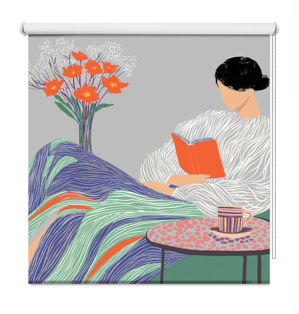 A decorative window roller shade featuring a vintage-style illustration of a woman in a white dress reading an orange book, with a striped cup on a table and orange flowers in a vase against a gray background.