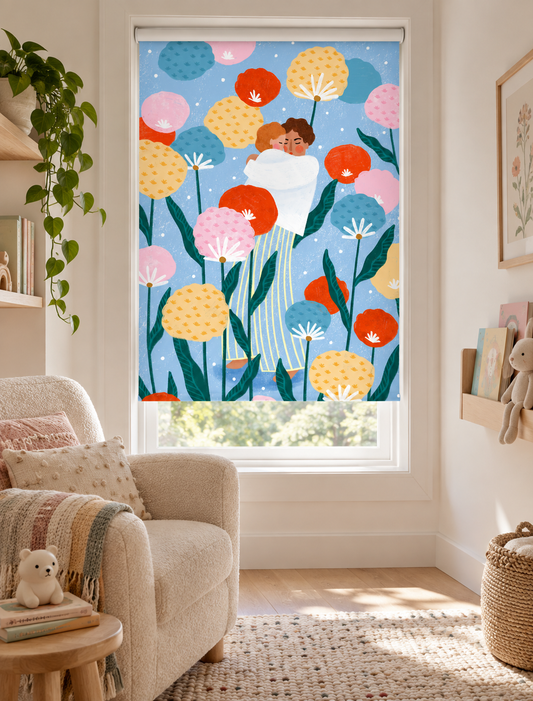 A colorful roller blind with a whimsical illustration of a couple among large dandelion-like flowers, shown installed on a window in a bright, modern living room.