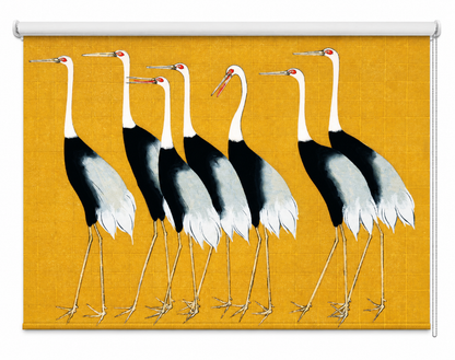 Printed roller blind featuring a traditional Japanese fine art design of a flock of elegant white and black cranes with red accents standing against a textured mustard yellow background, installed in a Japandi-style dining room