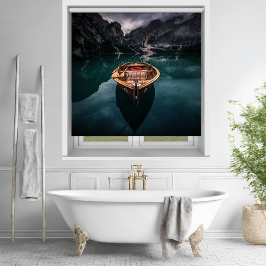 Printed roller blind featuring a dramatic, moody photograph of a single wooden rowboat floating on a dark, perfectly still lake surrounded by steep, misty mountains